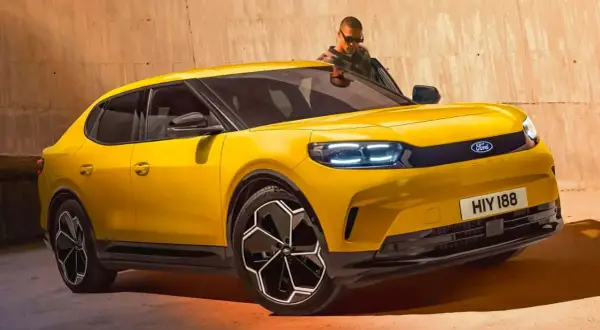 Nowy Ford Capri 2025 w jaskrawym żółtym kolorze, z nowoczesnymi światłami LED i stylowymi felgami. Mężczyzna w okularach wychodzi z samochodu.