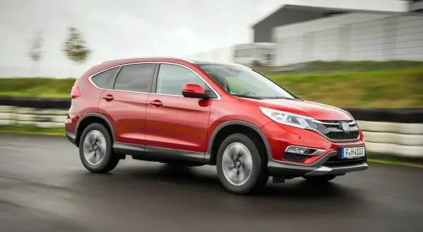 Czerwony Honda CR-V 4. generacji pędzi po torze wyścigowym, ukazując swoją dynamiczną sylwetkę.