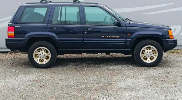 Granatowy Jeep Grand Cherokee ZJ z lat 90. na złotych felgach, gotowy na przygodę.