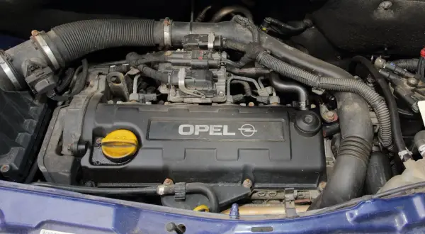 Silnik Opla Meriva A z widocznym napisem OPEL. Widać przewody, rury i żółty korek wlewu oleju.