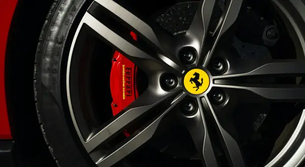 Felga z logo Ferrari, czerwony zacisk hamulcowy Brembo i opona Pirelli. Marka samochodu na i.