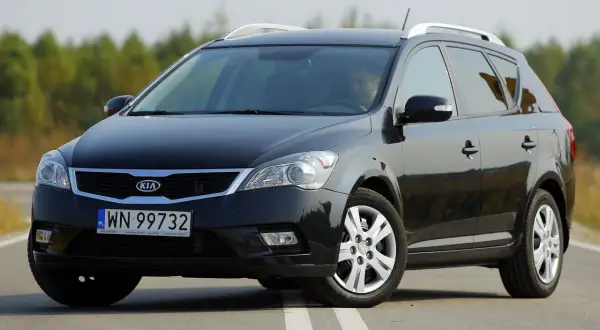 Czarny Kia Ceed 1. kombi na drodze, z kierowcą za kierownicą.