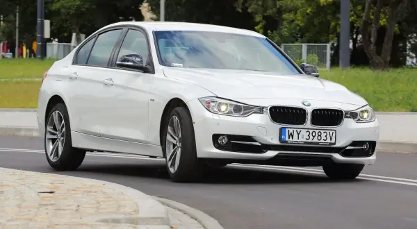 Białe BMW 318i z polskimi tablicami rejestracyjnymi WY 3983V jedzie po drodze.
