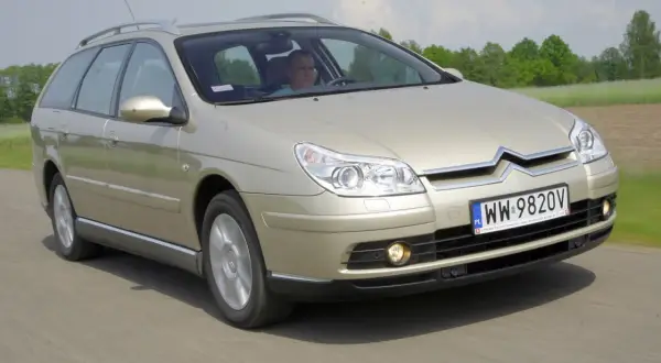 Złoty Citroen C5 kombi w ruchu drogowym. Kierowca za kierownicą. Wiele pozytywnych citroen c5 opinie potwierdza jego komfort.