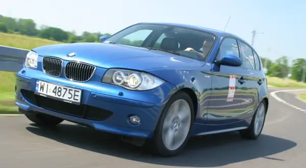Niebieskie BMW e81 z polskimi tablicami WI 4875E na zakręcie toru wyścigowego.