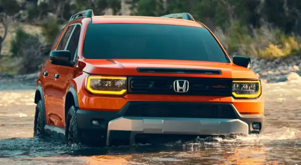 Pomarańczowy Honda Passport TrailSport pokonuje wodę, gotowy na przygodę.