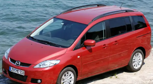 Czerwona Mazda 5 2.0 benzyna zaparkowana przy wodzie.