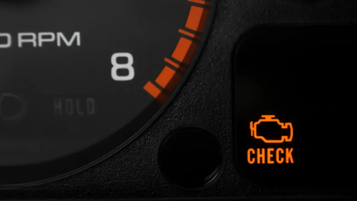 Pomarańczowa kontrolka silnika "CHECK ENGINE" na desce rozdzielczej samochodu.