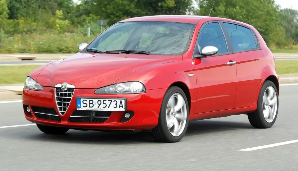Czerwone Alfa Romeo 147 1.9 JTD w ruchu, z widocznymi felgami w ruchu.