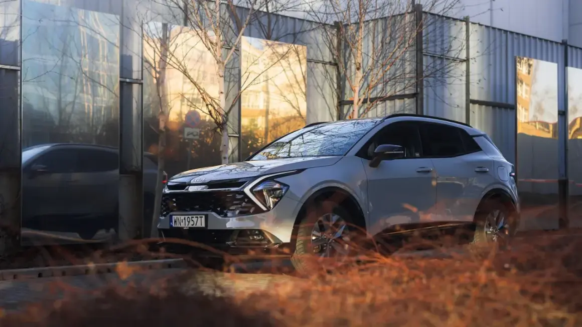 Nowy kia crossover odbija się w lustrzanych panelach, tworząc surrealistyczny krajobraz miejski.