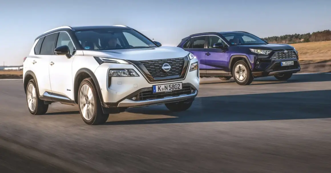 Biały Nissan X-Trail i fioletowy SUV jadą po drodze.