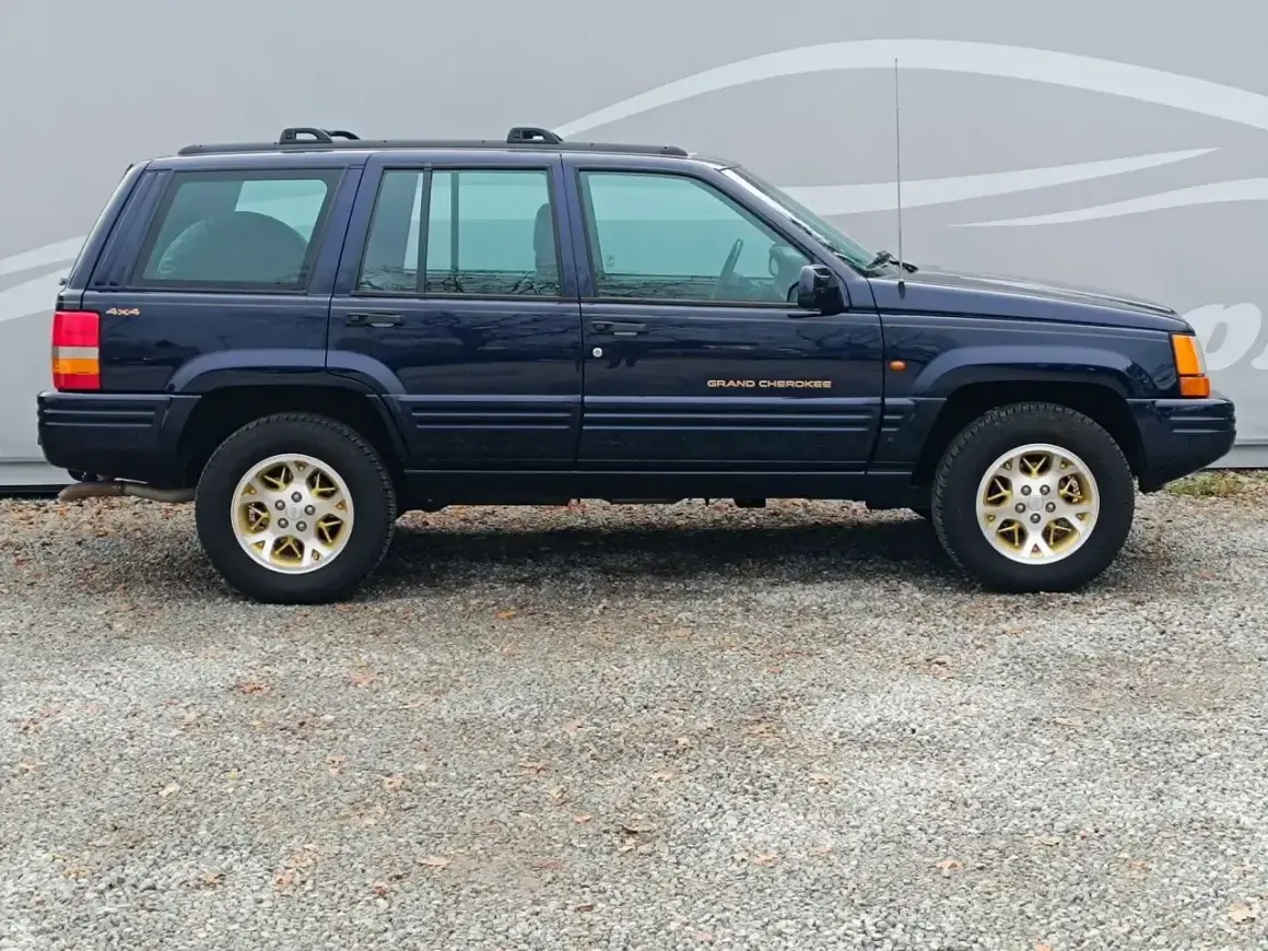 Granatowy Jeep Grand Cherokee ZJ z lat 90. na złotych felgach, gotowy na przygodę.