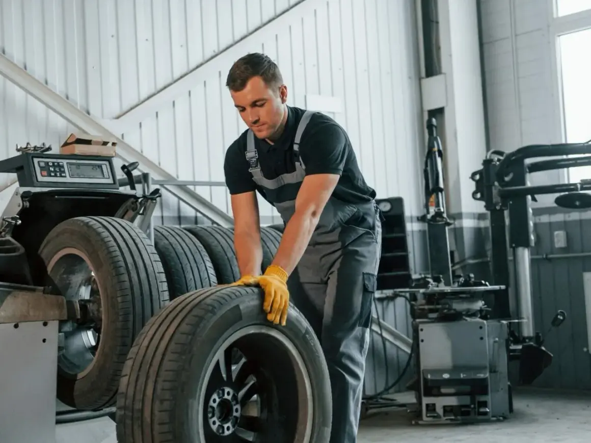 Mechanik w żółtych rękawiczkach przygotowuje opony Zeetex do montażu. Wulkanizacja w toku.