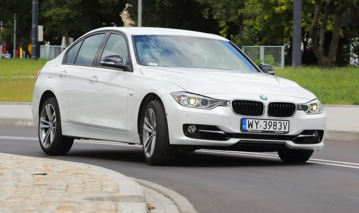 Białe BMW 318i z polskimi tablicami rejestracyjnymi WY 3983V jedzie po drodze.