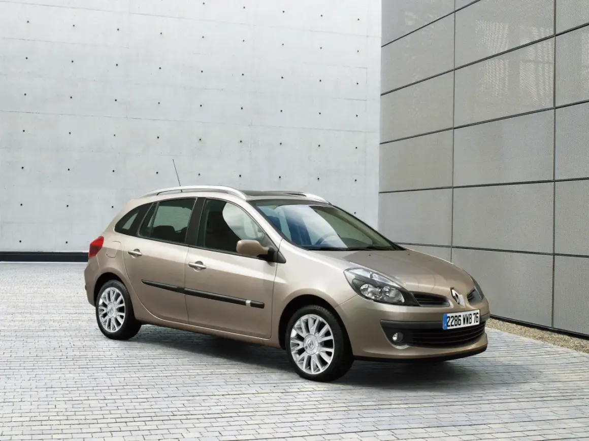 Beżowe Renault Clio 3 1.2 benzyna na tle nowoczesnej architektury.