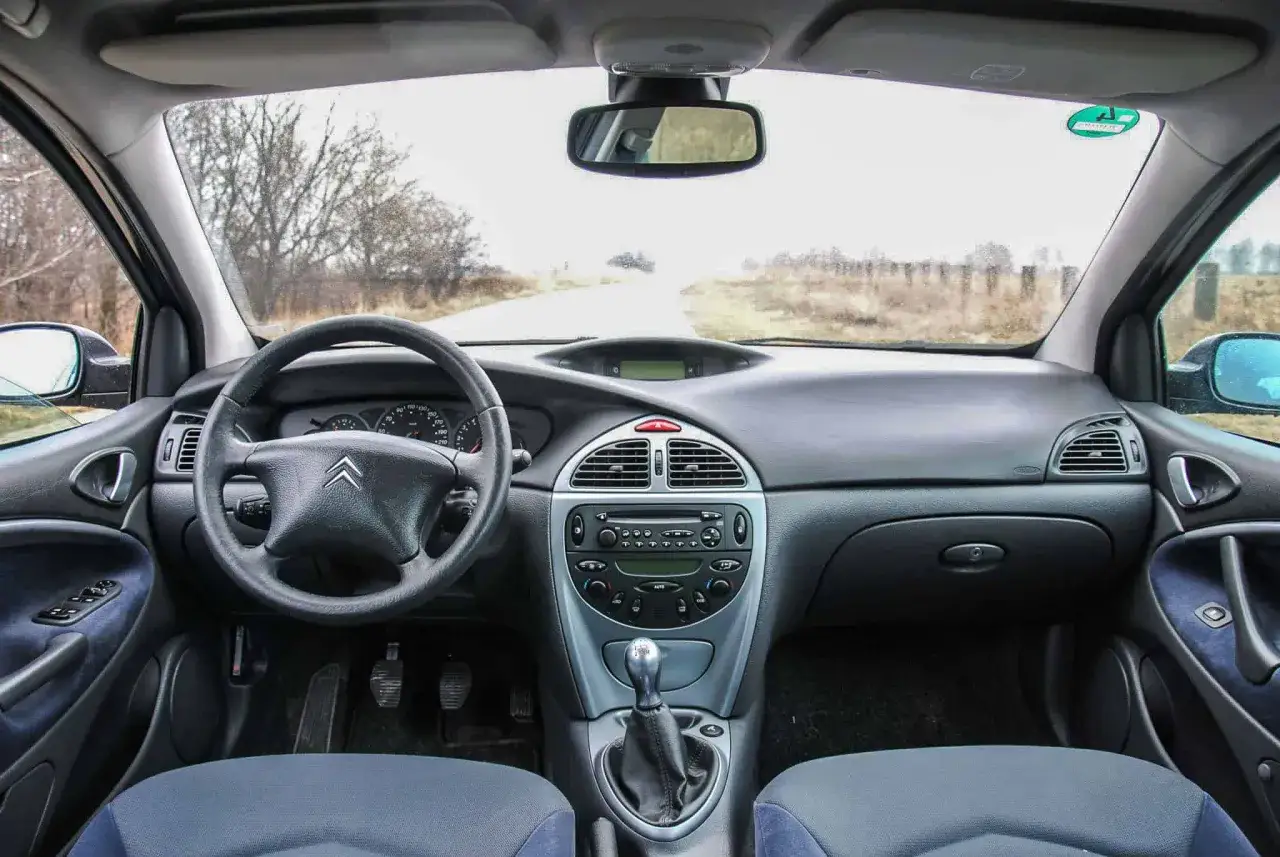 Wnętrze Citroena C5 X7 z widokiem na drogę. Kierownica, deska rozdzielcza i fotele.