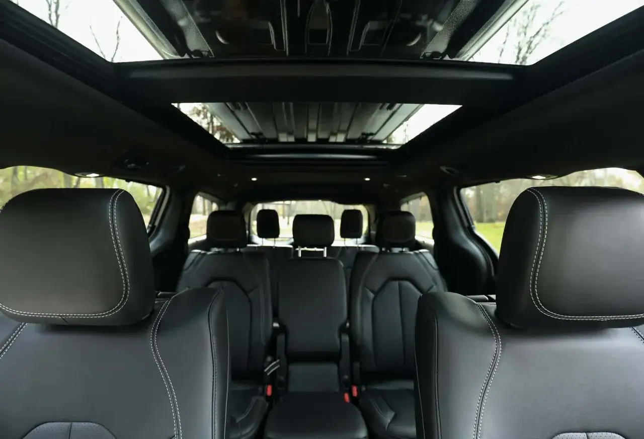 Wnętrze Chrysler Pacifica z czarną skórzaną tapicerką i panoramicznym dachem. Widok na fotele i podsufitkę.