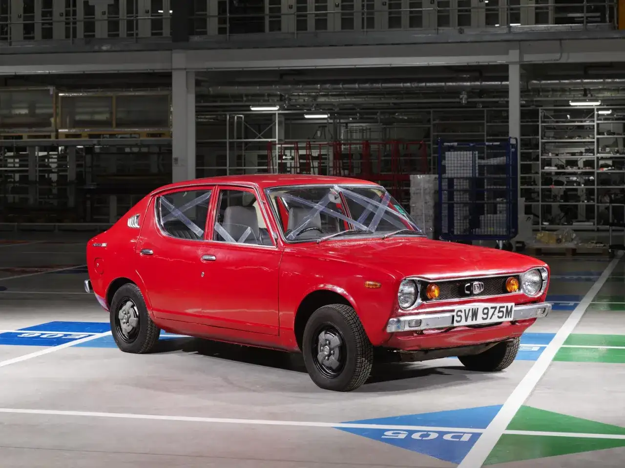 Czerwony Datsun 100A z lat 70. stoi na hali produkcyjnej.