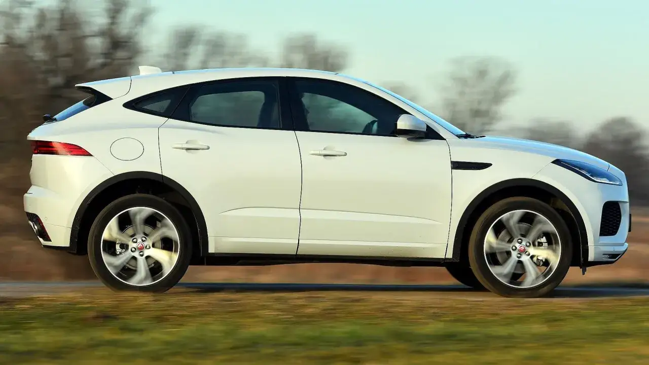 Biały Jaguar E-Pace pędzi po drodze, jego koła wirują w ruchu.