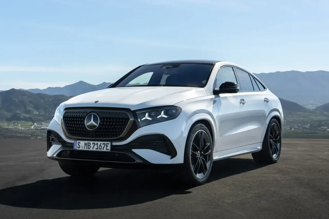 Biały Mercedes GLE 2026 Coupe z czarnymi felgami stoi na tle górskiego krajobrazu.