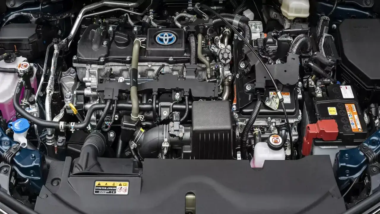 Silnik hybrydowy Toyoty z widocznym logo marki. Skomplikowana sieć przewodów i elementów, typowa dla nowoczesnych układów napędowych cng i hybryda.
