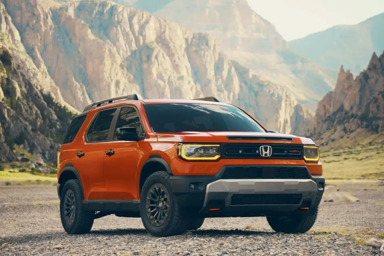 Pomarańczowy Honda Passport TrailSport gotowy na przygodę w skalistym, górskim krajobrazie.