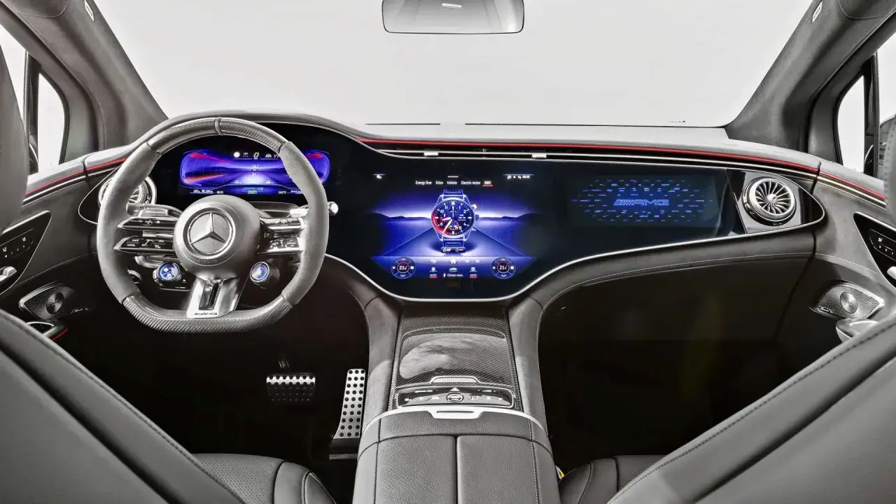 Wnętrze Mercedes EQE z wielkim ekranem MBUX Hyperscreen, wyświetlającym zegarek i logo AMG.