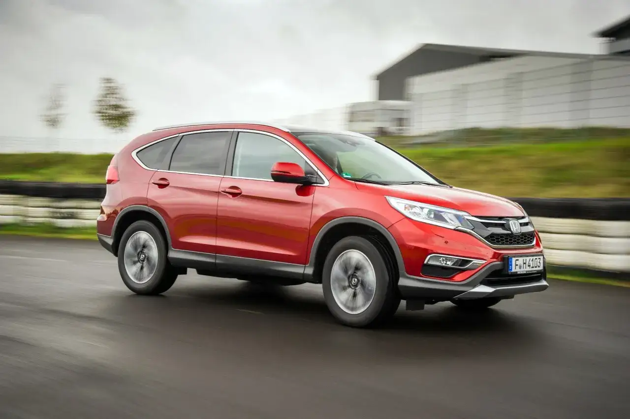 Czerwona Honda CR-V 4. generacji pędzi po torze wyścigowym, pokazując swoją dynamikę.