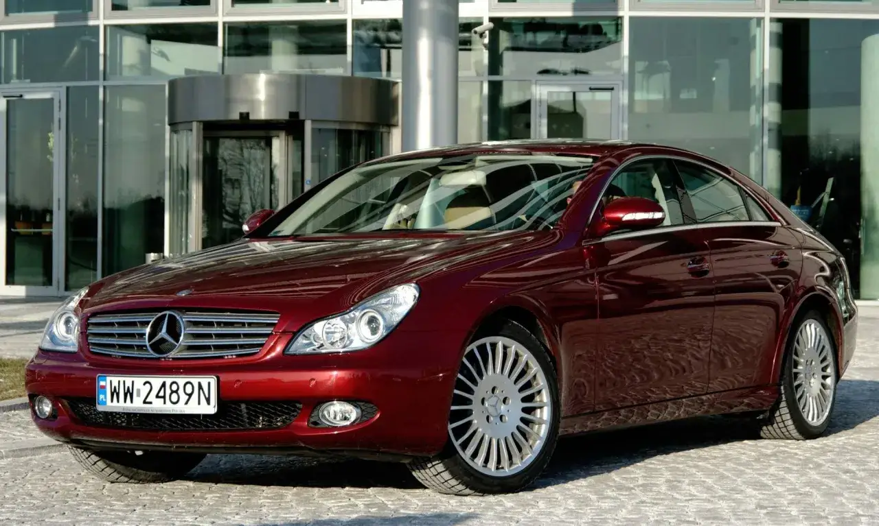 Elegancki, bordowy Mercedes CLS z silnikiem om642, zaparkowany przed nowoczesnym budynkiem z przeszkloną fasadą.