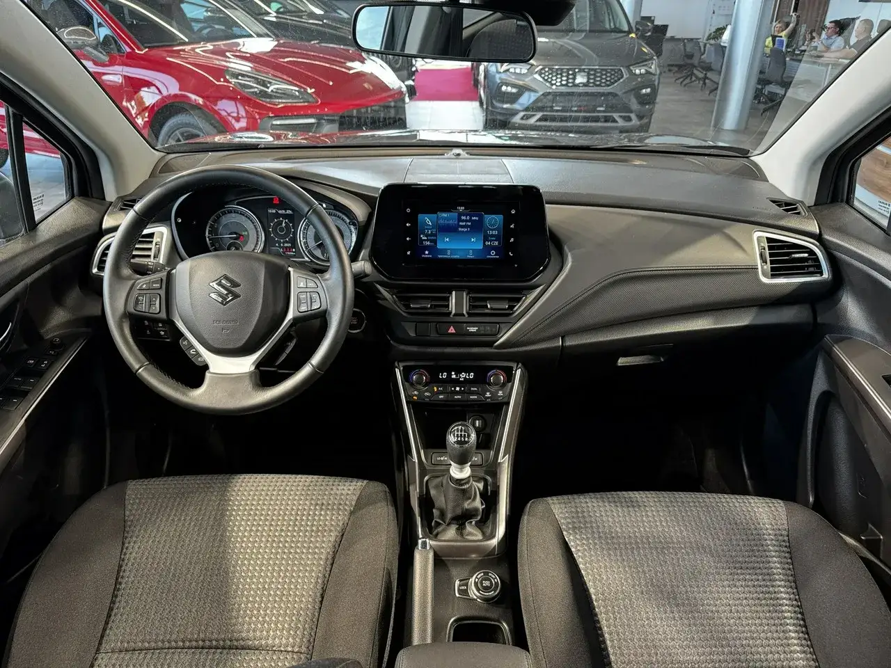 Wnętrze Suzuki SX4 1.6 benzyna. Widok na deskę rozdzielczą, kierownicę i fotele.