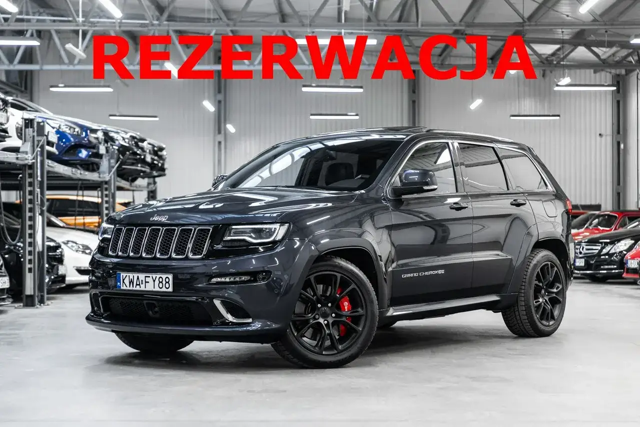 Ciemnoszary Jeep Grand Cherokee SRT z czerwonymi zaciskami hamulcowymi stoi w salonie samochodowym.