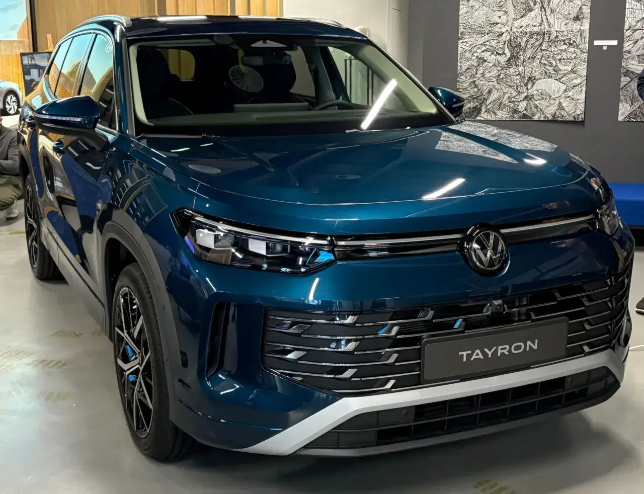 Błękitny Volkswagen Tayron, jeden z nowoczesnych volkswagen modele, prezentuje się elegancko z chromowanymi detalami i wyrazistym grillem.