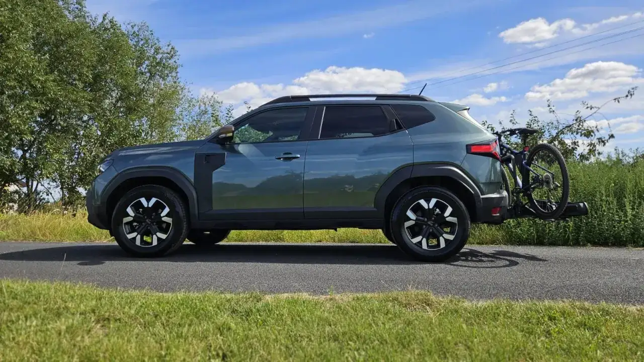 Zielony Dacia Duster 2 z rowerem na bagażniku, gotowy na przygodę w plenerze.