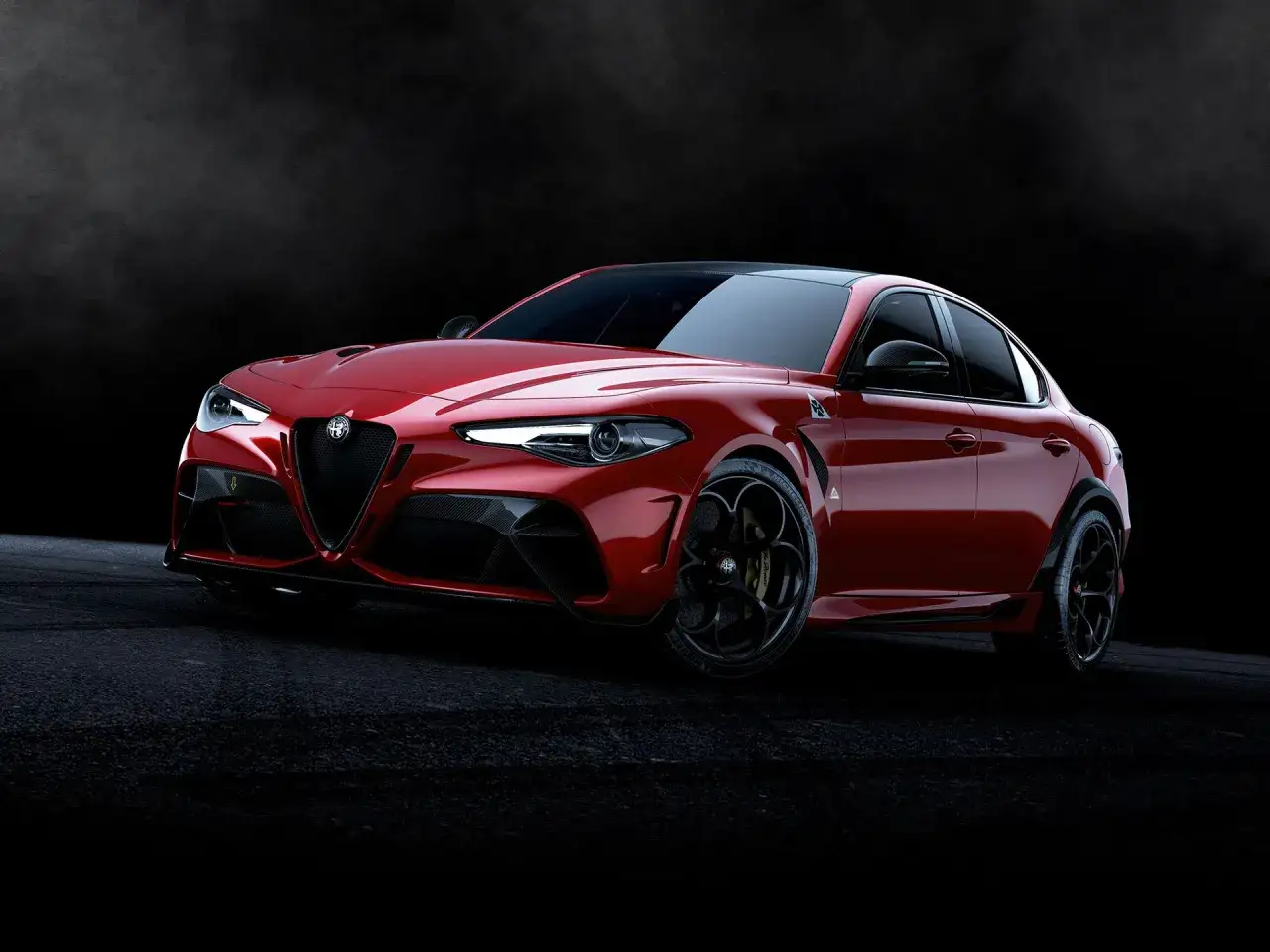 Czerwone Alfa Romeo Giulia GTAm z czarnymi felgami i detalami z włókna węglowego, prezentujące sportowy charakter na ciemnym tle.