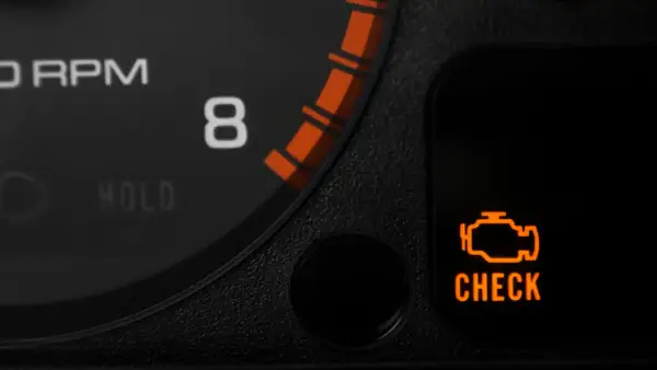 Pomarańczowa kontrolka silnika "CHECK ENGINE" na desce rozdzielczej samochodu.
