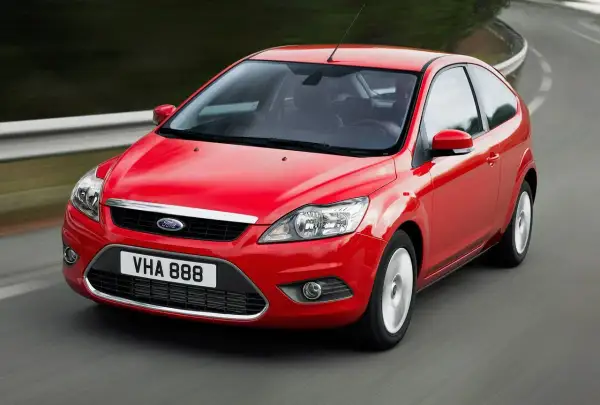 Czerwony Ford Focus MK2 1.6 benzyna w ruchu na krętej drodze.