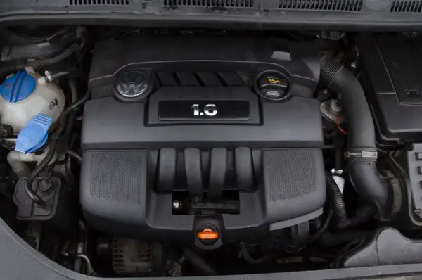 Silnik Volkswagena z oznaczeniem 1.6 MPI. Widoczny jest czarny plastikowy kolektor, logo VW i zbiornik płynu chłodniczego.