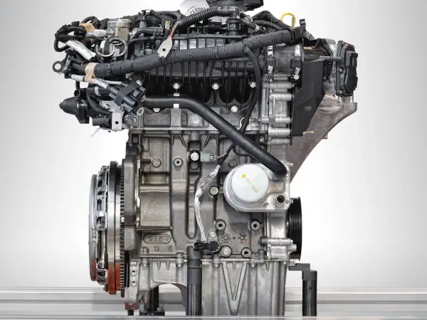Silnik Ecoboost z bliska, z widocznymi przewodami, filtrem oleju i elementami układu napędowego.