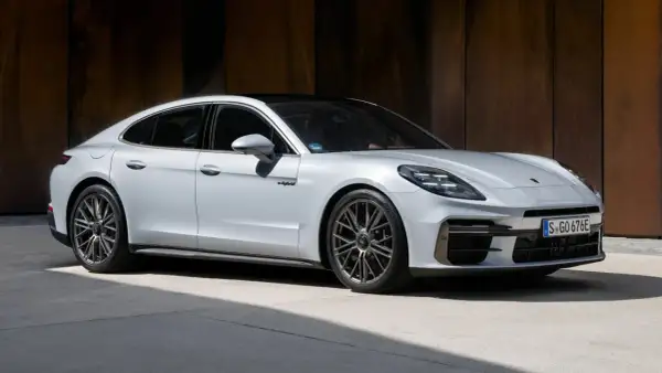 Biały Porsche Panamera Turbo S z czarnym dachem, zaparkowany przed rustykalną ścianą.