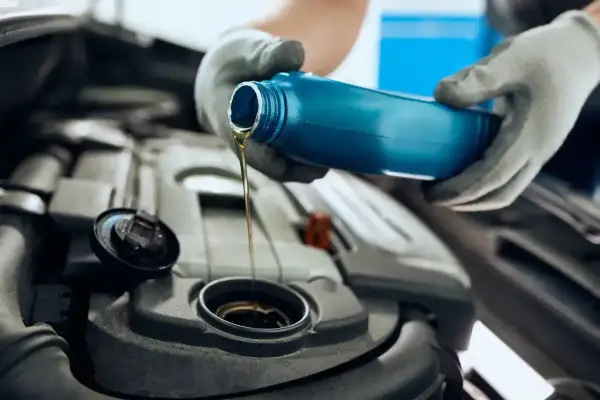 Ręce w rękawiczkach wlewają olej silnikowy 5W30 do silnika. Czy to Motul czy Castrol?