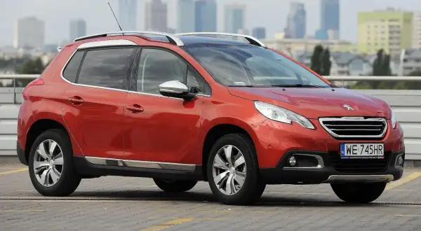 Pomarańczowy Peugeot 2008 na parkingu. Zastanawiasz się, jaki silnik wybrać do tego modelu?