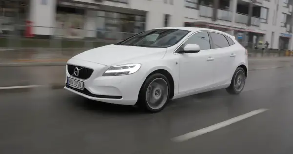 Białe Volvo V40 D3 w ruchu miejskim, na mokrej nawierzchni.